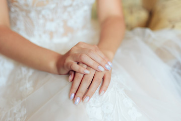 beautiful young hands of a bride with a manicure on a light background