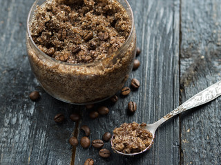 homemade coffee scrub with sugar and coconut oil in a jar on a wooden dark background