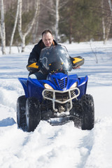 A man in winter clothes riding snowmobile in the winter forest