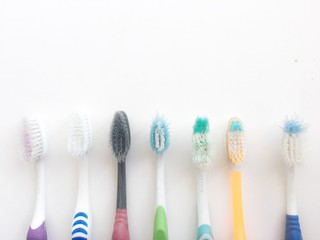 Used old colorful toothbrush on white background.