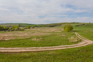 country road winds through the hills and into the woods © atasmsk