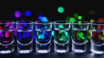 Glasses of vodka or tequila. In bar - neon background