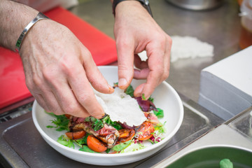the chef prepares a fresh salad with tomatoes and vegetables, grilled fish