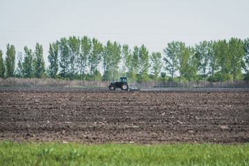 a large blue tractor prepares the land for planting