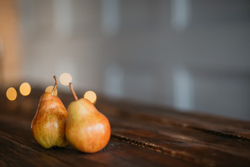 Beautiful ripe tasty pears on a large kitchen wooden table with a garland of lights. A beautiful screen saver for an article about wholesome food, a concept for a food blog, a saver for a pastry chef