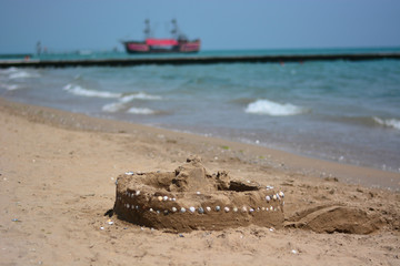 A sand castle and in the background a sailing ship ready to sail