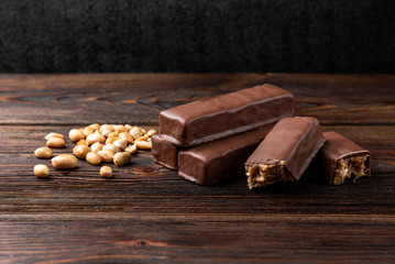 Chocolate bar with caramel and peanut on dark wooden background. 