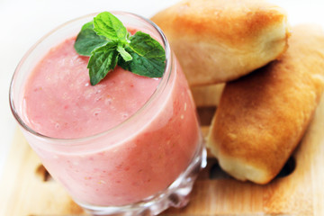 Strawberry banana pink yogurt with a sprig of mint and mouth-watering pies, selective focus