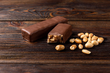 Chocolate bar with caramel and peanut on dark wooden background. 
