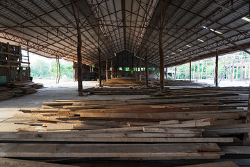 Piles of wooden planks in open warehouse near construction site