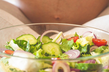 Pregnancy and healthy organic nutrition. Pregnant woman enjoying fresh vegetable salad in bed, free space. Concept of expectation and health.