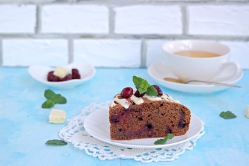 Dessert, homemade chocolate cake with cherries on a white plate. Decorated with white chocolate and cherry. Selective focus