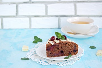 Dessert, homemade chocolate cake with cherries on a white plate. Decorated with white chocolate and cherry. Selective focus