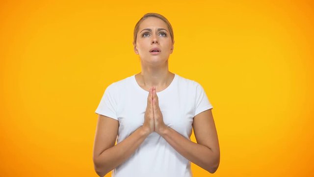 Young female praying joining hands and closing eyes, asking help, expectations