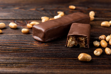 Chocolate bar with caramel and peanut on dark wooden background. 