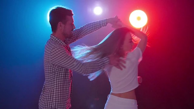 Concept of dance and relationships. Young beautiful couple dancing sensual dance in color light
