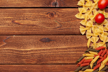 Pasta and ingredients on wooden background with copy space. Top view.