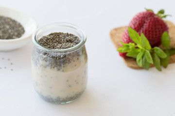 Healthy vegan chia pudding in a jar with fresh strawberry on the table