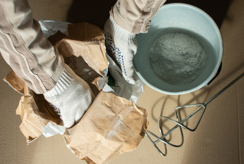 Man builder prepares a mixture for putty, bag with gypsum putty and drill mixer