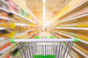 Empty green shopping cart with supermarket aisle with seasoning and cooking vegetable oil bottles...