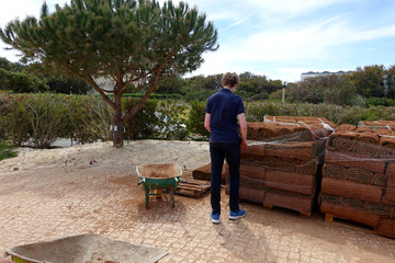 Boy unwrapping new rolls of turf from pallet