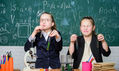 Girls study chemistry. Make studying chemistry interesting. Microscope and test tubes on table....