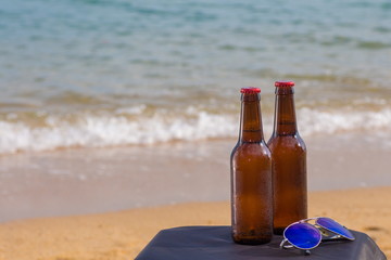 Two Brown Beer bottles in the sand on the beach on the background of the sea and sky