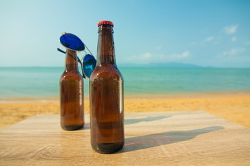 Two Brown Beer bottles in the sand on the beach on the background of the sea and sky