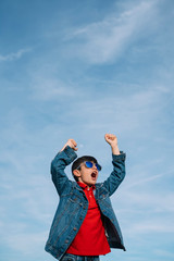 Happy kid with sunglasses holding hands up