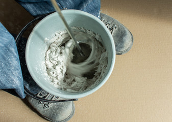 Man builder mixes gypsum putty in a bucket