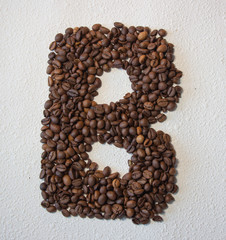 Image of roasted coffee beans shaped alphabet on a white background