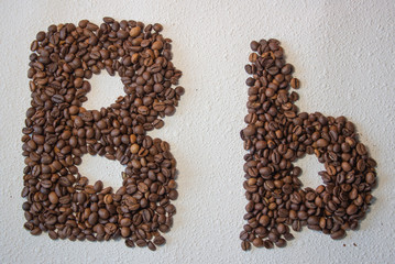 Image of roasted coffee beans shaped alphabet on a white background