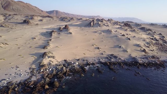 Las Tortolas beach aerial footage at Atacama Desert the sunset ray lights illuminate this amazing and idyllic beach in the middle of the desert, an arid awe landscape crashed by Pacific Ocean waters