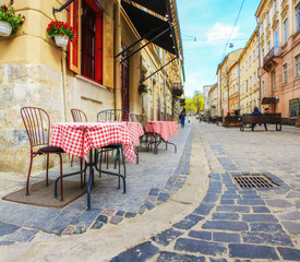 Outdoor cafe in the old town. Summer cafe in the narrow old street.  Vintage tables on narrow paved...