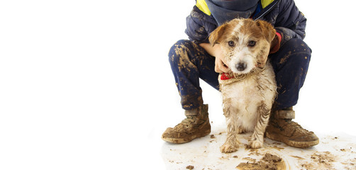 DIRTY  JACK RUSSELL DOG AND LITTLE BOY CHILD.  AFTER PLAY IN A MUD PUDDLE. ISOLATED SHOT AGAINST...