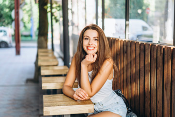 Pretty young brunette girl relaxing in street cafe outdoor.