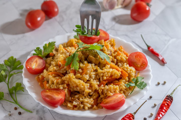 Pilaf in the plate, tomatoes and hot peppers on a light background. Central Asian cuisine. Horizontal orientation.