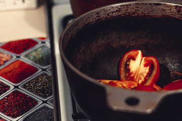 Tomato slices in the shape of a heart are cooked in a cast-iron cauldron, symbolizing the love of cooking