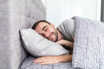 Handsome young man sleeping in bed at home