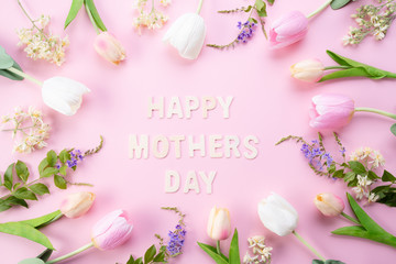 Obraz na płótnie Canvas Happy mothers day concept. Top view of pink tulip flowers in frame with happy mothers day text on pink pastel background. Flat lay.