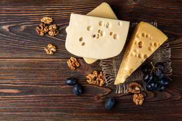 Cheese and walnut on dark wooden background.