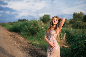 beautiful young girl in a summer dress in a field on a background of green grass