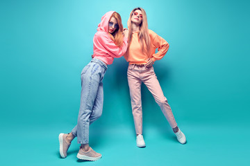Two hipster Girl in trendy colorful neon fashion Outfit Fooling Around in Studio. Young Tomboy...
