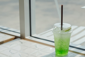 Kiwi Italian Soda on marble table near glass window.