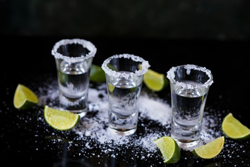 Tequila shot with lime and salt on black background