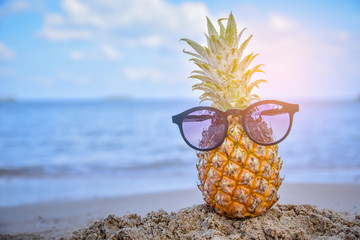Sun glass is on pineapple at beach sea view background,Summer holiday concept