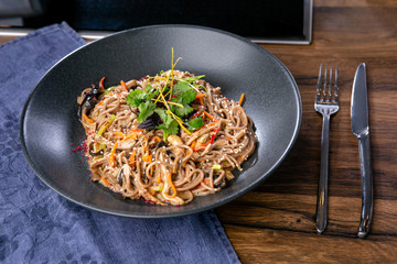 Buckwheat noodles with duck and mushrooms. Asian cuisine. The work of a professional chef. Dish from a restaurant or cafe menu. Close-up