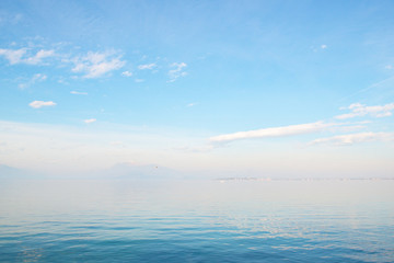 Obraz premium Desenzano del Garda, Italy. Calm beautiful view of italian lake Garda. Amazing landscape in fog with water, sky and mountains. Panorama of gorgeous Lake Garda surrounded by mountains. Heaven on Earth.