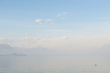 Fototapeta na wymiar Desenzano del Garda, Italy. Calm beautiful view of italian lake Garda. Amazing landscape in fog with water, sky and mountains. Panorama of gorgeous Lake Garda surrounded by mountains. Heaven on Earth.