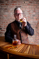 Man tasting whisky on a Bar in Front of a red stone wall